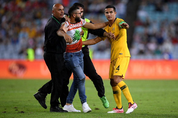A pitch invader is restrained by security as he reaches Tim Cahill of the Socceroos during the match.