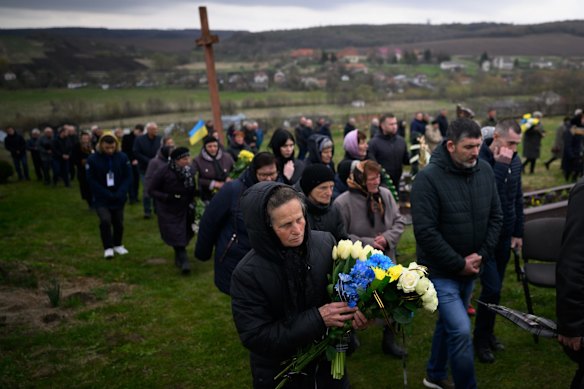 Family members, friends and neighbours walk through the cemetery ahead of the burial for fallen soldier Kobryn Oleg, 39, at the Church of Saint Jehoshaphat in Dev'yatnyky.