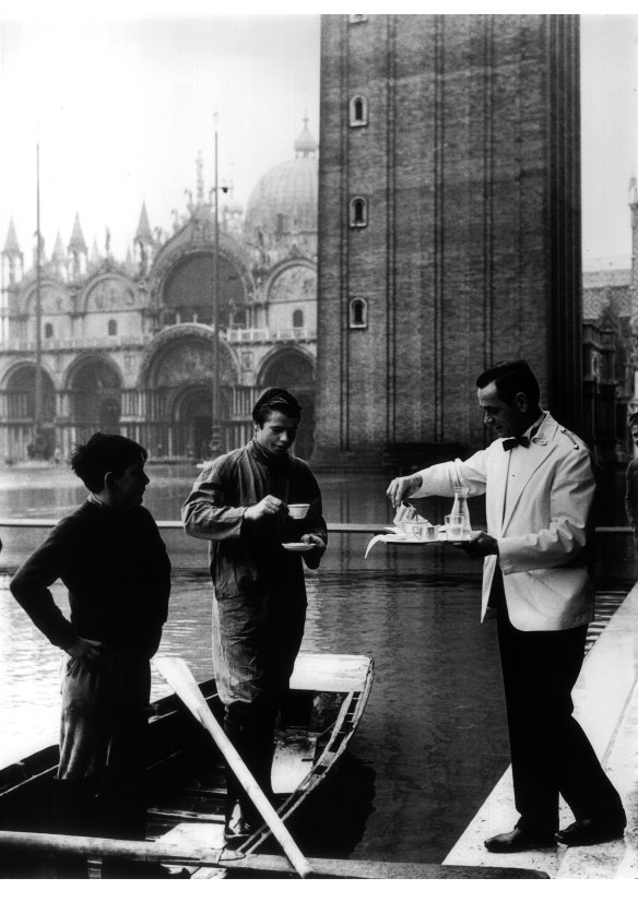A waiter serves coffee during a flood in Venice.