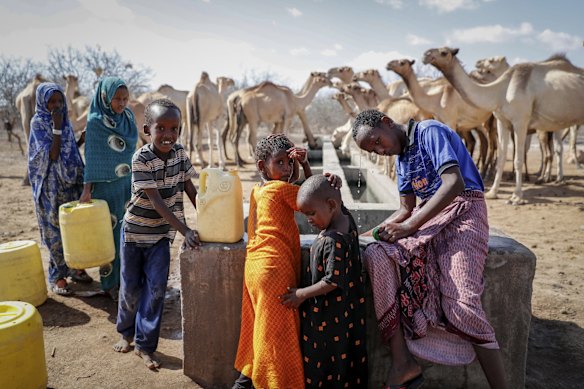 Herder children who look after their family's camels cool off and fill plastic containers with water from a water point in the desert near Dertu, Wajir County, Kenya.