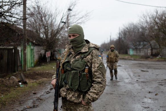 Ukrainian servicemen carry weapons in Svitylnia.