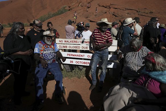 Traditional Owners pose for photos after placing the new sign of the permanent closure of the Uluru climb on the final day the climb is allowed.