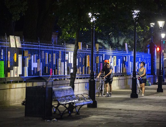 People walk past signs placed in the fence of Jackson Square after protesters gathered in solidarity with Minnesota demonstrators after the death of George Floyd, in New Orleans.