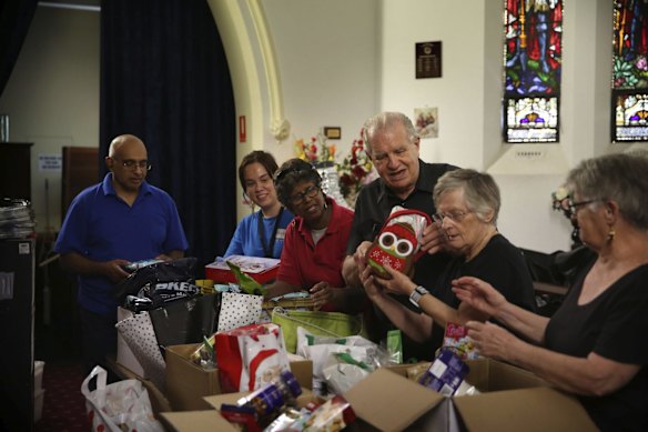 Reverend Bill Crews (centre) and volunteers of the Exodus Foundation sort through Christmas donations at their Ashfield parish prior to Christmas Day. Due to social distancing requirements this year, the gifts will be made available without contact.