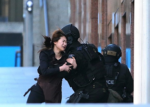 A hostage runs to armed tactical response police officers for safety after she escaped from Lindt cafe.
