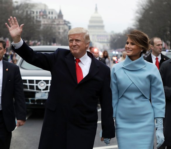 President Donald Trump waves as he walks with first lady Melania Trump during the inauguration parade on Pennsylvania Avenue in Washington.