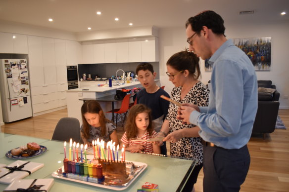 Joshua, his wife Kirsten and their three children chant blessings just after lighting six candles to signify the "sixth" day of Hanukkah.