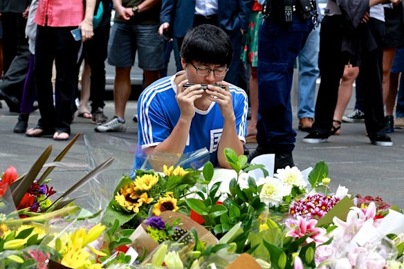 A man lays flowers at the makeshift memorial in Martin Place. 
