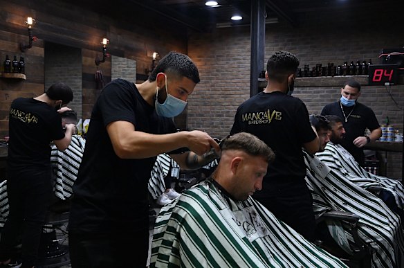 Mancave Barbershop barber Hardi Zahr, right, cuts a customers hair in Westfield Bondi Junction shopping centre on the first day of relaxed COVID-19 restrictions for fully vaccinated people.