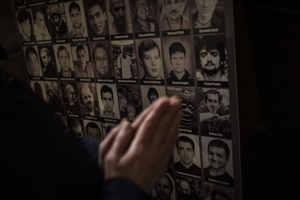 A Christian worshipper prays in front of pictures of fallen soldiers at the Saints Peter and Paul Garrison Church in Lviv. The memorial is dedicated to Ukrainian soldiers who died after 2014.
