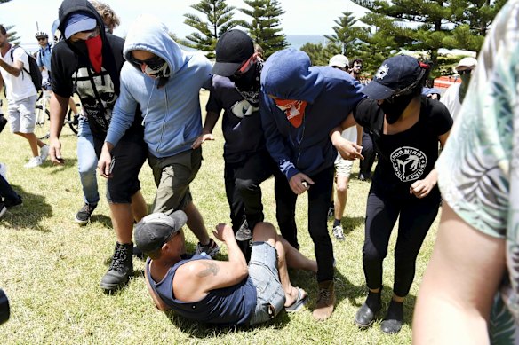 Anti racism protestors stand over an opposing protestor.