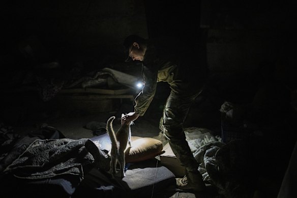 Ukrainian serviceman Anton pets a cat in a basement previously used by Russian soldiers as a temporary base in the village of Malaya Rohan, Kharkiv.