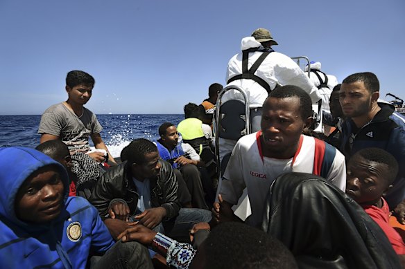 Refugees watch on as they are transferred to the MY Phoenix rescue ship off the Libyan coast. The men were on a wooden boat in an attempt to cross to Europe.