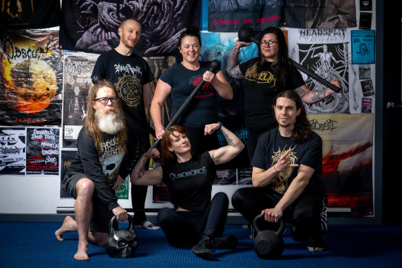 Elissa Jewell and her clients pose in front of death metal posters. 