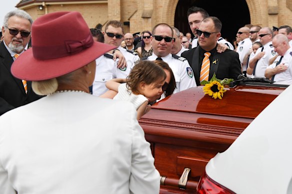 Charlotte O'Dwyer, the young daughter of Rural Fire Service volunteer Andrew O'Dwyer, kisses her fathers casket during the funeral for NSW RFS volunteer Andrew O'Dwyer.