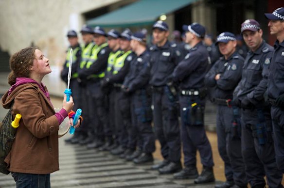 A lone protester surveys a line of police officers.