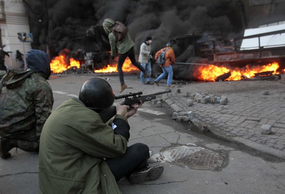 An anti-government protester shoots during clashes with riot police outside Ukraine's parliament in Kiev, Ukraine, Tuesday, Feb. 18, 2014. Thousands of angry anti-government protesters clashed with police in a new eruption of violence following new maneuvering by Russia and the European Union to gain influence over this former Soviet republic.