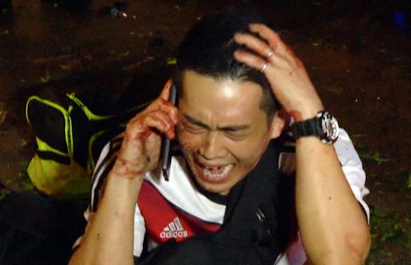 This image taken from AP video shows a man talking into a mobile photo after an explosion in central Bangkok.