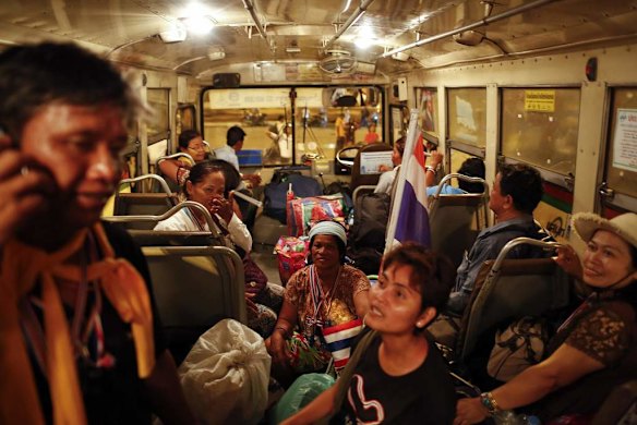 Anti-government protesters board a bus at the Royal plaza to take them back home after the coup.