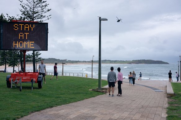 Northern Beaches residents look on as a black hawk helicopter flies over Dee Why Beach after lockdown was announced at 5pm on December 19.