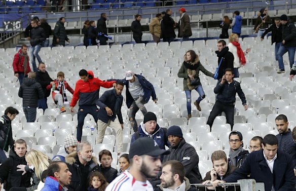Soccer fans jump across seats to get to the field after an explosion occured outside the stadium.
