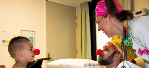 Canberra Hospital paediatric patient Jesse Boulton receives a visit from clown doctors Pablo Latona (Dr Snooze) and Ruth Pieloor (Dr Whoops).