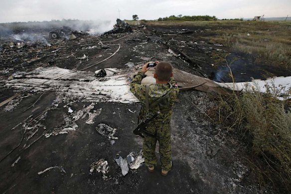 An armed pro-Russian separatist takes pictures at the site of a Malaysia Airlines Boeing 777 plane crash.