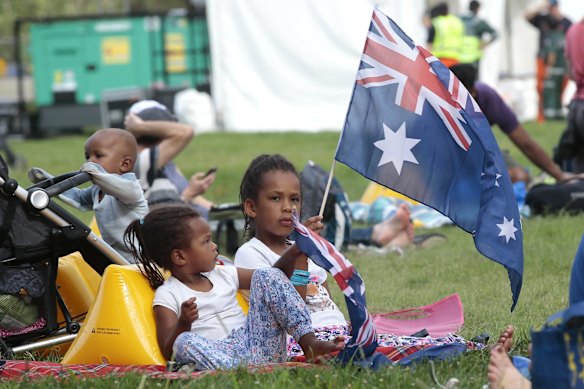 Yuew Baak, 1, Achol Baak, 3, and Akon Baak, 7, of Crystalbrook playing with an Australian flag.
