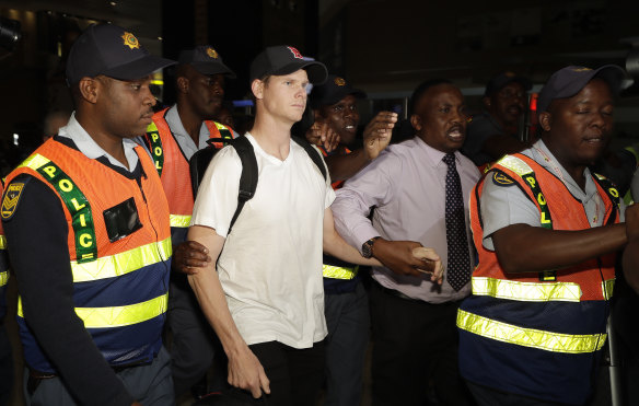 Steve Smith was escorted by police officers to a departure area at OR Tambo International airport in Johannesburg.