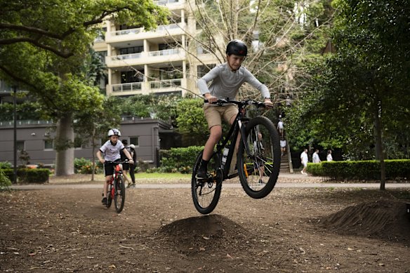 A group of kids having fun jumping their bikes, in Rushcutters bay Park.