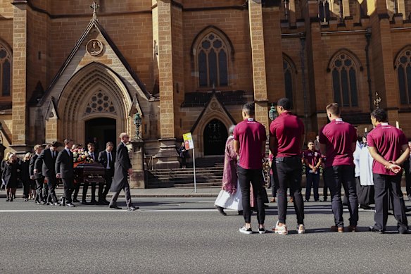 The coffin is carried through a guard of honour including junior Manly players.