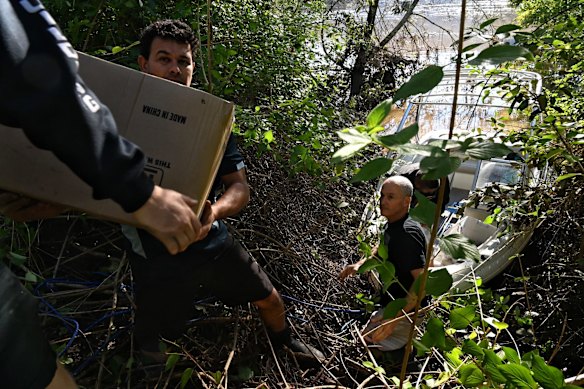 Cabin owners and residents of Leetsvale Caravan Park passing supplies to a boat to get over to the still isolated caravan park on the Hawkesbury River.
