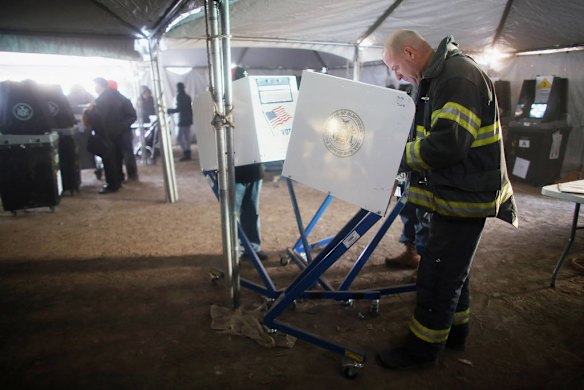 Rockaway resident and firefighter Terence O'Donnell marks his ballot in a makeshift tent set up as a polling place in the storm ravaged suburb of Rockaway New York