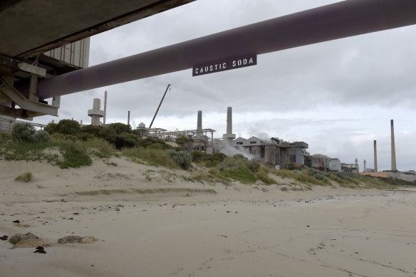 A pipe with a sign reading 'caustic soda' runs along a jetty at the Alcoa Corp in Kwinana.