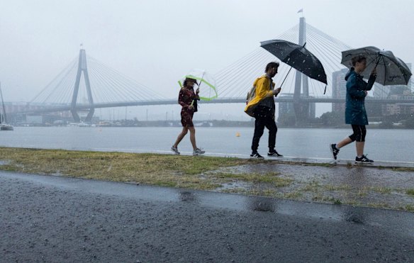 People make their way around the Blackwattle Bay as torrential rain and storms hit Sydney.