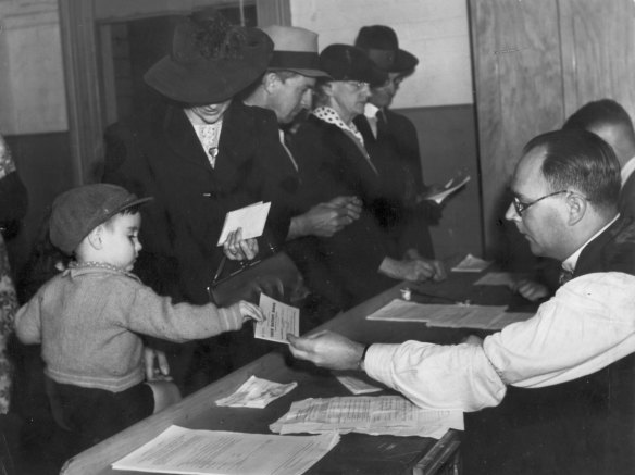 “Little Norman Mooney receiving his ration book from office at Woolloomooloo. June 13, 1942.” Ration books were issued to all holders of Civilian Identity Cards or Aliens Registration Cards and their dependants.