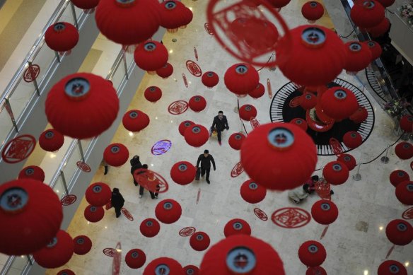 Customers walk through the hall of a local shopping mall beneath red lanterns put up as Spring Festival decorations in Nanjing, Jiangsu province, China.