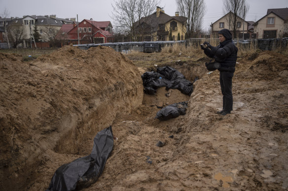A journalist films footage of a mass grave in Bucha, on the outskirts of Kyiv.
