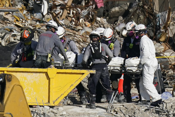 Search and rescue personnel remove remains on a stretcher.