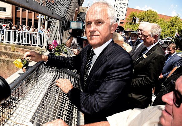 Prime Minister Malcolm Turnbull takes in the scene as he throws a rose from the bridge at Granville.