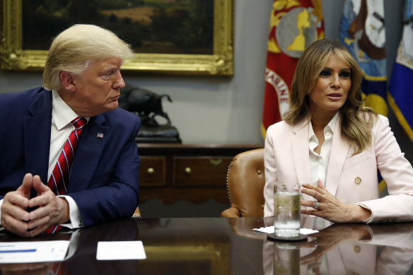 President Donald Trump listens as first lady Melania Trump speaks during a briefing.