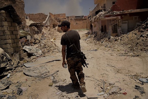 An Iraqi Special Forces soldier inspects the damage along a street.