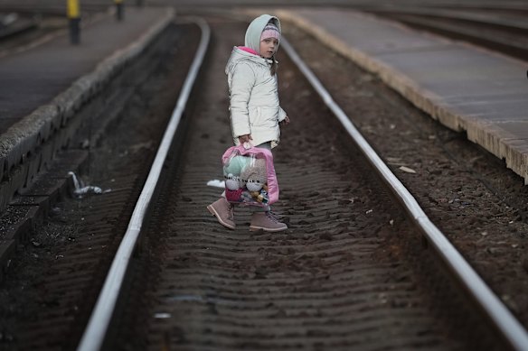 A young refugee girl fleeing Ukraine walks across the tracks as she arrives at the border train station
 in Zahony, Hungary. 