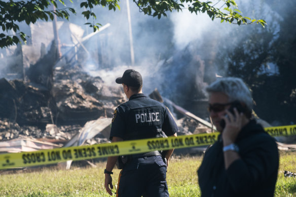 Police stand guard near the remains of a house that exploded due to severe flooding.