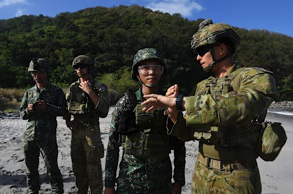Australian Army Sapper Nicholas Field (right) and Sapper Justin Letta (2nd from left) with the 2nd Combat Engineer Regiment explain the timing procedure of a controlled explosion.