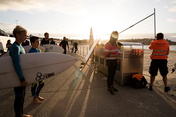 Surfers await while the barricade is removed at Bondi beach.