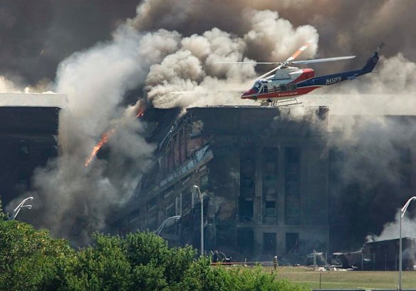 A rescue helicopter surveys damage to the Pentagon as firefighters battle flames after an airplane crashed into the U.S. military Headquarters outside of Washington in this September 11, 2001 photo.