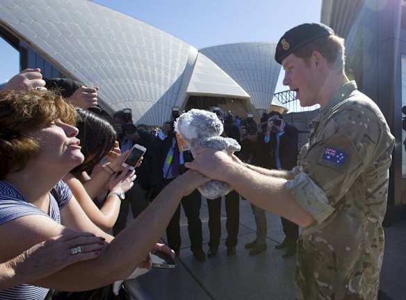 Britain's Prince Harry receives a toy koala from from Sydneysider Anne Woods (L) as he greets well-wishers during a visit to Sydney's Opera House in Australia
