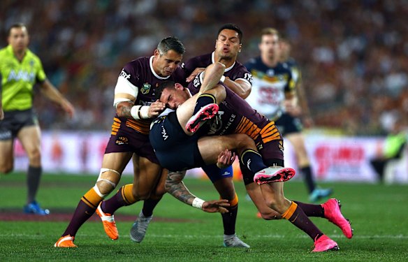 Kyle Feldt of the Cowboys is tackled by Corey Parker and Darius Boyd of the Broncos.