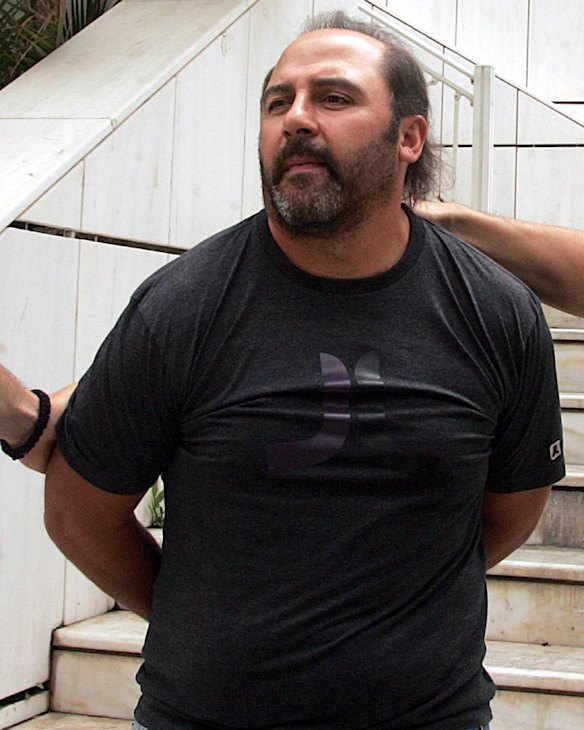 Tony Mokbel is led away by Greek police officers at the time of his extradition hearing.